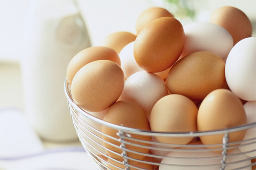 Brown and white hen eggs in a wire basket
